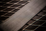 A herringbone pattern stainless damascus steel billet laying on steel rack
