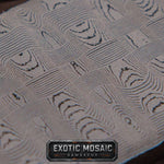 A close-up of a textured mosaic damascus pattern with repeating geometric and organic wave-like motifs in gray, black, and off-white tones. A dark badge at the bottom reads 'EXOTIC MOSAIC DAMASCUS'.