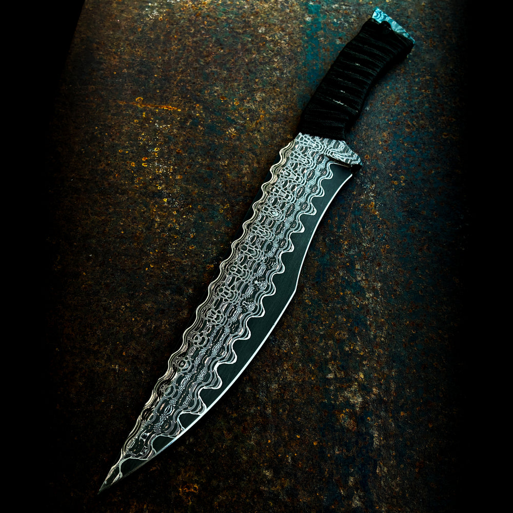 Knife with decorative copperhead san mai blade held by a gloved hand on a dark background