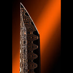 A close-up studio shot of a knife blade tip with a dark Damascus-style patterned finish, set against a dramatic orange gradient background.