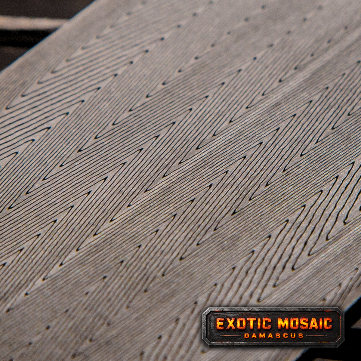 Close-up of herringbone pattern damascus with 'exotic mosiac' label.