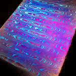 a ladder patterned flat bar of titanium damascus with bright colors on black background