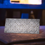 Stainless Lytic Damascus billet with layered ripples sitting in front of forge