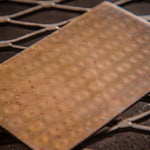 close up image of a raindrop pattern mokume gane flat bar on a metal corrugated background