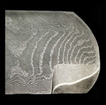 a stainless san mai billet in random pattern with a bevel ground into it which reveals the core steel