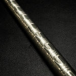a reverse reptilian pattern damascus round bar with black textured background