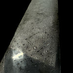 a billet of carbon damascus in riptide pattern on black background