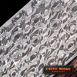 billet of seismic pattern damascus billet sitting on anvil in front of forge