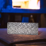 billet of stainless damascus sitting on anvil in front of flaming forge