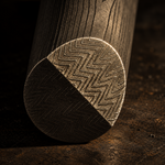 close up image of a stainless damascus sharktooth pattern round bar sitting on a metal rusted table