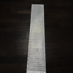 sharktooth pattern damascus billet textured surface from acid etching on a dark wood floor background