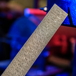 a image of spirograph damascus with circular layers with the vegas forge shop in background under a blue and red lighting