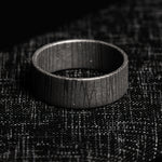 stainless damascus ring with spirograph pattern on a textured black background