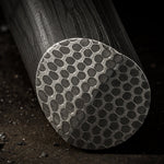 a close up on the face pattern of a stainless honeycomb pattern damascus round bar sitting on metal table with metal scale on table
