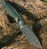 Folding knife with stainless steel Spirograph Damascus blade, detailed geometric pattern, and titanium handle resting on wood.