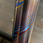 a twisted damtanium round bar made with layers of grade 2 titanium and grade 5 titanium, also known as titanium damascus