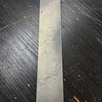 a billet of stainless twist damascus steel on black table backround