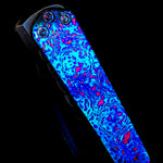 Glowing blue and pink patterned titanium damascus or damtanium clip on a black background