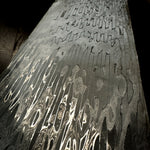 a billet of stainless virus pattern damascus forged by vegas forge on a brown wooden table