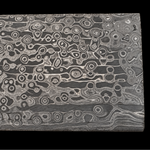 a billet of stainless steel virus pattern san mai with flowing stainless steel layers on black background