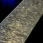 Close-up of the Vortex Damascus pattern, showing tightly layered bright lines curling around dark oval shapes.